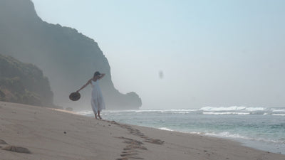 Video de ROUCLÊ: mujer con vestido blanco y sombrero caminando por la orilla de una playa al atardecer